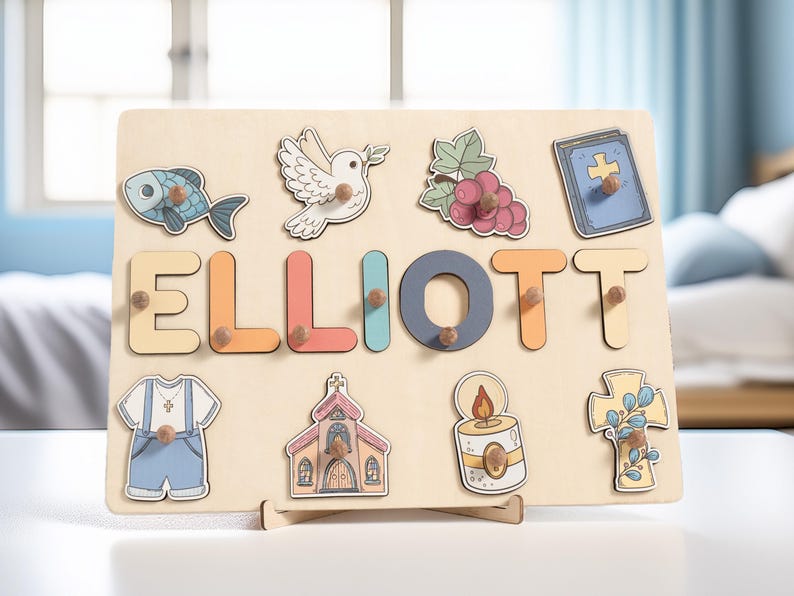 Puede incluir: Un tablero de rompecabezas de madera con el nombre "ELLIOTT" escrito en letras de colores. El tablero presenta varios s&iacute;mbolos religiosos, incluyendo una paloma, un pez, una iglesia, una cruz, una vela y uvas.