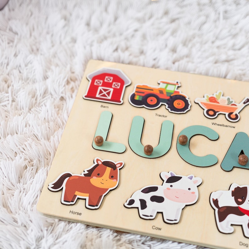 May include: A wooden personalized puzzle with the name Luca. The puzzle features farm animals, a barn, a tractor, and a wheelbarrow. The puzzle pieces are shaped like the letters of the name and the animals.