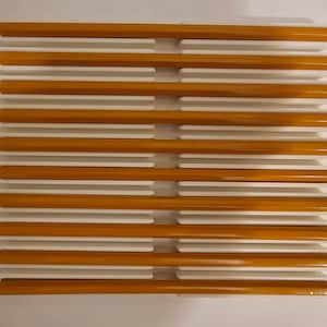 May include: A rectangular pencil holder with a grid design. The holder is white with slots to hold pencils. The pencils are yellow with a brown tip and eraser. The pencils are arranged horizontally.