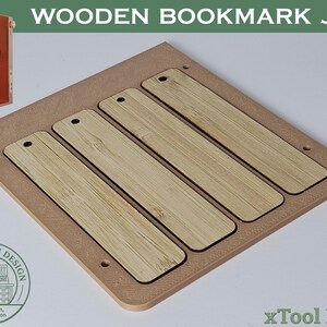 Pode incluir: Um gabarito de marcador de livros de madeira com quatro ranhuras para marcadores. O gabarito é feito de madeira castanha clara e tem uma forma retangular. O texto "WOODEN BOOKMARK JIG" está no topo. A imagem também inclui o texto "xTool F1/F2".