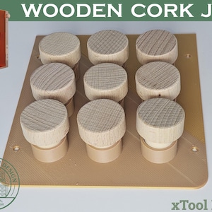 May include: A wooden cork jig with nine corks arranged in a 3x3 grid. The corks are light brown with a circular top and a cylindrical base. The jig is a light brown color and has a rectangular shape. The image also includes an orange machine and text that reads "WOODEN CORK JIG".