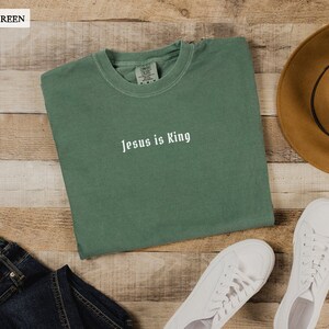 May include: A light green t-shirt with the text "Jesus is King" in white lettering.