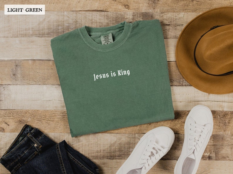 May include: A light green t-shirt with the text "Jesus is King" in white lettering.