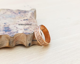 Könnte beinhalten: Ein kupferfarbener Ring mit einem sich wiederholenden geometrischen Wabenmuster. Der Ring wird auf einer Holzoberfläche präsentiert. Der Shop-Name "925BangleShop" ist sichtbar.