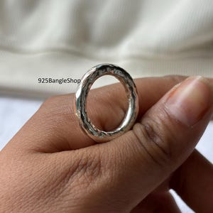 May include: A hammered silver ring with a textured surface. The ring is round and has a slightly irregular shape. The text "925BangleShop" is visible in the background.
