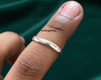 May include: A silver ring with a wavy design. The ring is worn on a finger. The text "925BangleShop" is visible in the image.