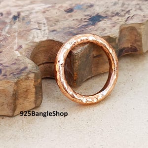 Könnte beinhalten: Ein gehammerter Kupferring mit strukturierter Oberfläche. Der Ring hat eine warme, rötlich-braune Farbe und ein schlichtes, klassisches Design. Der Text "925BangleShop" ist unten links sichtbar.