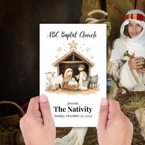 May include: A white card with the text "ABC Baptist Church" and "The Nativity" with a watercolor illustration of the Nativity scene. The card is held by a person. The date "Sunday, December 20, 2024" is also printed on the card.