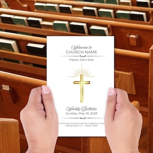 May include: A white church bulletin with gold accents is held in front of a church pew. The bulletin reads "Welcome to CHURCH NAME" and "Weekly Bulletin Sunday, May 18, 2028." A gold cross is featured on the bulletin.