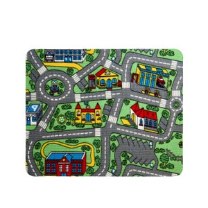 Puede incluir: Una alfombra de juego verde con una escena de ciudad que presenta edificios, carreteras y árboles. La alfombra está diseñada para que los niños jueguen con coches y camiones de juguete.