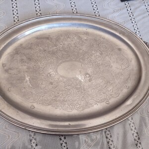 Könnte beinhalten: Ein ovales Serviertablett aus Silber mit verziertem Rankenmuster und zwei Griffen.