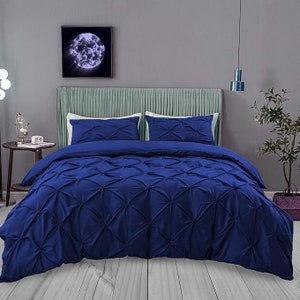 May include: A navy blue duvet cover with a pleated design. The duvet cover is on a bed with two matching pillowcases.