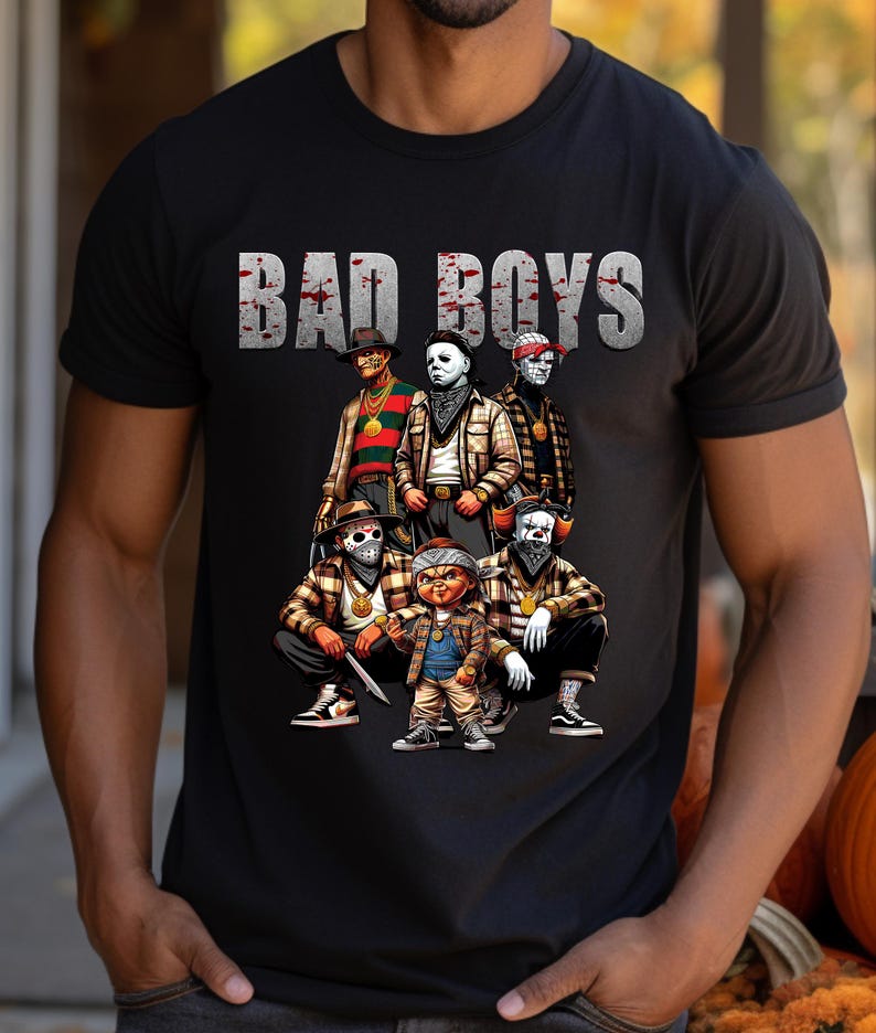 Man wearing a black Halloween t-shirt featuring the Bad Boys of Horror PNG design with Freddy Krueger, Michael Myers, Pinhead, Jason Voorhees, Pennywise, and Chucky. The characters are dressed in brown plaid streetwear with bandanas, sneakers, and gold chains, standing under bold gray blood-splattered text that reads ‘Bad Boys.’ Horror PNG artwork displayed on apparel.