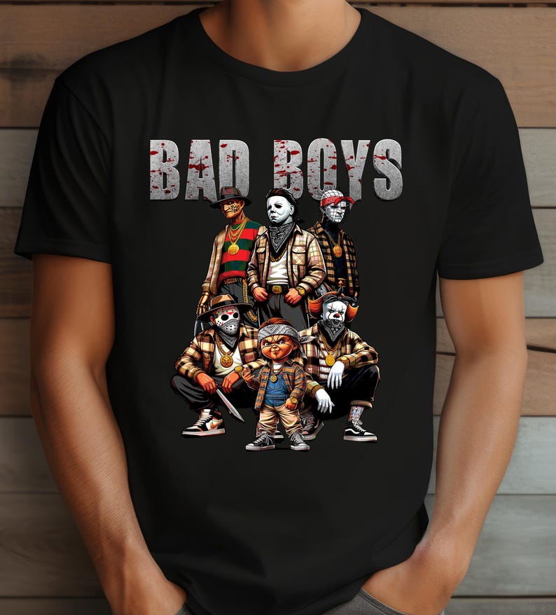 Man wearing a black Halloween t-shirt featuring the Bad Boys of Horror PNG design with Freddy Krueger, Michael Myers, Pinhead, Jason Voorhees, Pennywise, and Chucky. The characters are dressed in brown plaid streetwear with bandanas, sneakers, and gold chains, standing under bold gray blood-splattered text that reads ‘Bad Boys.’ Horror PNG artwork displayed on apparel.