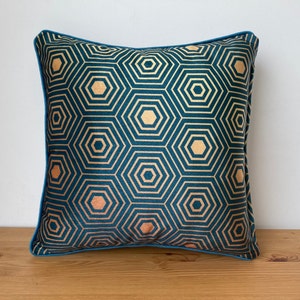 Puede incluir: Almohada de terciopelo azul turquesa con un patr&oacute;n geom&eacute;trico dorado. La almohada tiene un ribete azul turquesa.