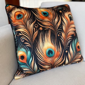 May include: Square cushion with a black trim. It displays a colourful peacock feather pattern in orange, teal, and gold on a black backdrop. The cushion is placed on a white sofa.