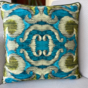 Puede incluir: Una almohada decorativa con un patrón ikat azul, verde y blanco.