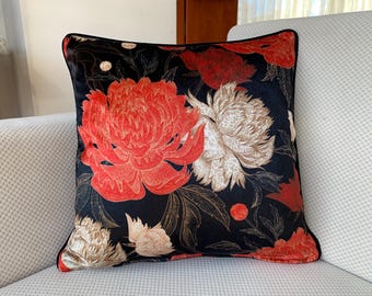 May include: Black velvet pillow with a red and white floral pattern. The flowers are large and detailed, and the background is a deep black.