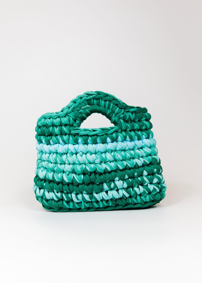 May include: A green and blue crocheted handbag with a single handle.