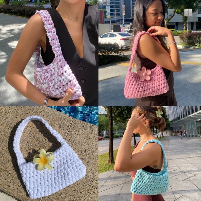 May include: Three crocheted handbags in different colours: pink with white, white with a white flower, and light blue. The bags are all small and have a simple, casual design.