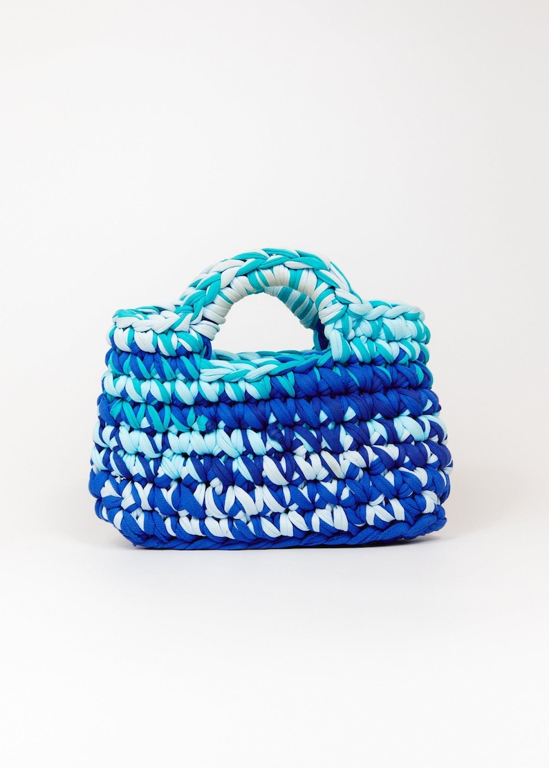 May include: A small blue, white, and turquoise crocheted handbag with a single handle.