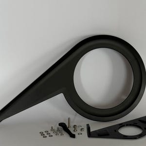 Op de afbeelding: Zwarte kunststof fietskettingbeschermer met montagemateriaal. De kettingbeschermer is ontworpen om kleding te beschermen tegen de ketting.