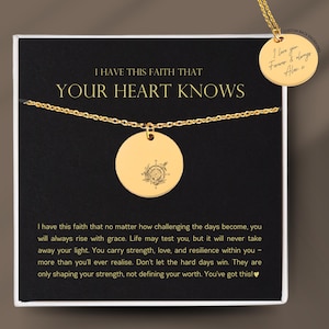 May include: A gold pendant necklace with a circular charm, featuring a compass design. The necklace is presented on a black card with the text "I HAVE THIS FAITH THAT YOUR HEART KNOWS". A smaller charm is engraved with "I love you Forever & always".