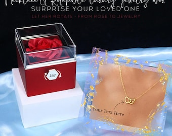 Può includere: Un portagioie rotante rosso con coperchio trasparente, contenente una rosa rossa. La scatola è su un piedistallo bianco. Una collana d'oro con cerchi intrecciati è esposta su una carta trasparente con dettagli dorati. Il testo sulla carta recita "Your Text Here".