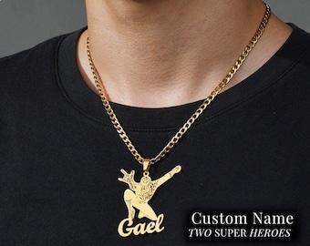 Pode incluir: Colar de corrente dourada com um pingente que apresenta uma silhueta do Homem-Aranha e o nome "Gael" escrito em itálico. O texto "Custom Name Two Super Heroes" também é visível.
