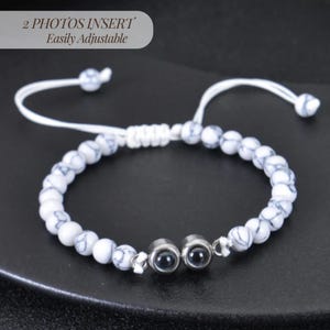 May include: White marble bead bracelet with two photo insert charms. The bracelet is adjustable with a white cord.