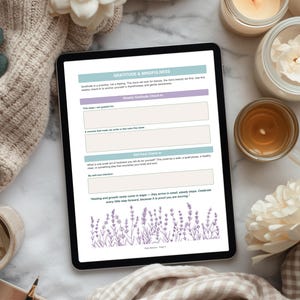 Op de afbeelding: Een digitale tablet met een pagina van een dankbaarheids- en mindfulness-dagboek. De pagina bevat prompts voor wekelijkse dankbaarheids- en zelfzorgcontroles, met lavendelillustraties. De sc&egrave;ne omvat kaarsen, bloemen en een zachte beige deken.