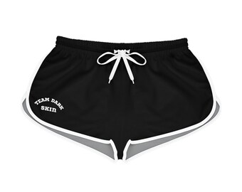 Op de afbeelding: Zwarte sport shorts met een witte bies en een wit geborduurd logo met de tekst "Team Dark Skin".
