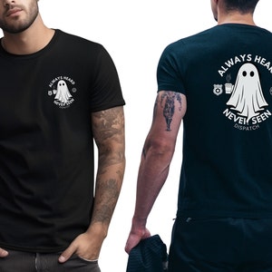 May include: Black t-shirts with a white graphic of a ghost and the text "ALWAYS HEARD NEVER SEEN DISPATCH". The design is on the front and back of the shirts. The shirts are short-sleeved and made of a dark fabric.