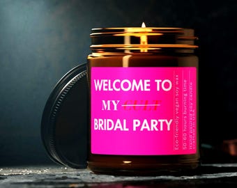 Peut inclure: Une bougie en pot de verre marron avec une mèche allumée et un couvercle noir. La bougie porte une étiquette rose vif avec le texte "WELCOME TO MY BRIDAL PARTY". La bougie est fabriquée avec de la cire de soja végétalienne écologique et a une durée de combustion de 50 à 60 heures.