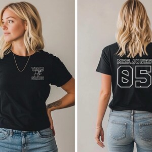 Peut inclure: Deux t-shirts noirs avec du texte blanc. Le premier t-shirt dit "Team Fifth Grade" et le deuxième t-shirt dit "Mrs. Jones 05".