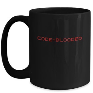 以下が含まれることがあります： 「CODE-BLOODED」と赤いピクセルデザインが施された黒いセラミック製のコーヒーカップです。
