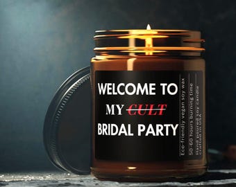 Peut inclure: Une bougie en cire de soja allumée dans un bocal en verre avec un couvercle noir. L'étiquette indique "WELCOME TO MY CULT BRIDAL PARTY" en texte blanc et rouge. La bougie est coulée à la main et fabriquée avec de la cire de soja végétalienne écologique.