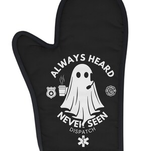 May include: Black oven mitt with a white ghost holding a cup of coffee and a phone. The text reads "Always Heard Never Seen Dispatch" with police, fire, and medical symbols.