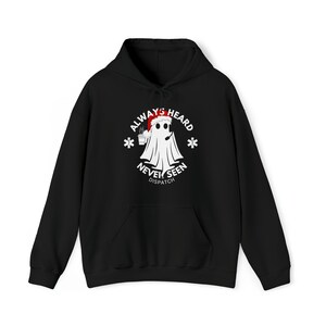 May include: Black hooded sweatshirt with a white graphic of a ghost wearing a Santa hat and holding a cup of hot cocoa. The text around the ghost reads "Always Heard Never Seen Dispatch".