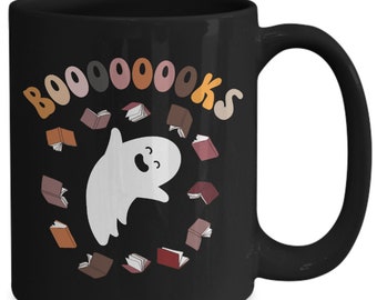 Può includere: Tazza da caffè nera con un fantasma bianco circondato da libri e il testo "BOO-OOO-OOKS".