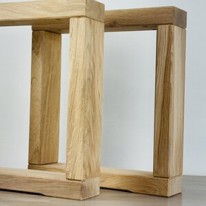 May include: Two rectangular furniture legs constructed from light-colored natural wood with a visible grain pattern. Each leg features a sturdy frame design with two vertical posts connected by a horizontal base and a top support beam.
