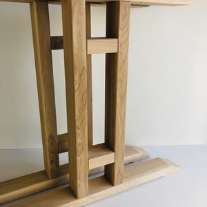 May include: A light-colored wooden table base featuring a flat rectangular top supported by four vertical posts connected by horizontal crossbars, resting on two parallel horizontal feet with beveled ends, showcasing a natural wood grain texture.