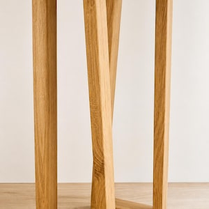 May include: A set of two light brown oak wood table legs featuring a rectangular frame design. Each leg structure consists of two vertical posts connected by a horizontal base and a top support bar, with a visible natural wood grain texture.