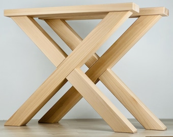 May include: Two wooden table legs with an X-shaped design. The legs are made of natural wood and have a light brown color.