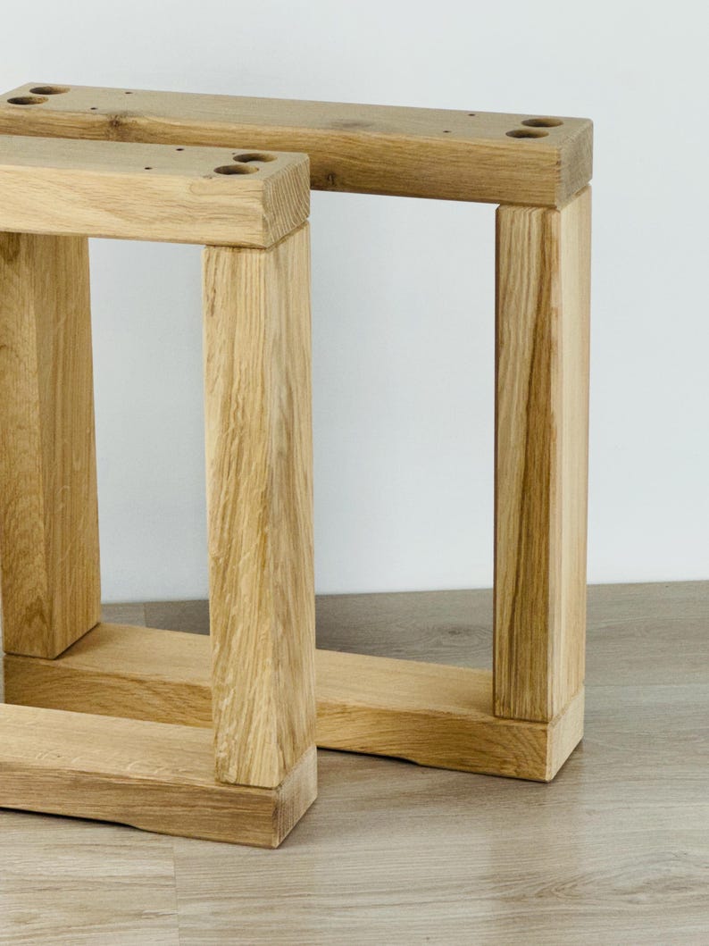 May include: Two rectangular furniture legs crafted from light-colored natural wood with a visible grain pattern. Each leg features a sturdy frame construction with two vertical posts connected by a horizontal base and a top support bar with pre-drilled holes.