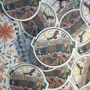 May include: A set of round stickers with a pastel pink background and a green border. The stickers feature a whimsical illustration of a bear, whale, and flying bird with the text "Protect Planet Earth" in a banner.