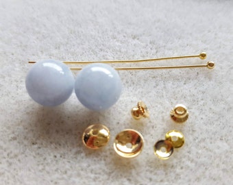 May include: Two light blue round beads with gold earring posts and backs. There are also four gold earring backs.