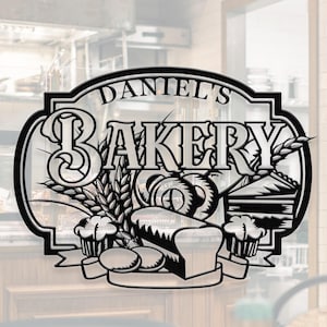 Könnte beinhalten: Ein schwarzes Metallschild für "Daniel's Bakery" mit einem dekorativen Design von Backwaren, darunter Brot, eine Brezel, Weizenähren, Muffins und ein Stück Kuchen. Das Schild ist für die Wand- oder Türmontage konzipiert.