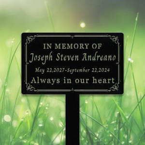 May include: Black metal garden memorial plaque with gold lettering. The plaque reads "In memory of Joseph Steven Andreano May 22, 2027 - September 22, 2024 Always in our heart."