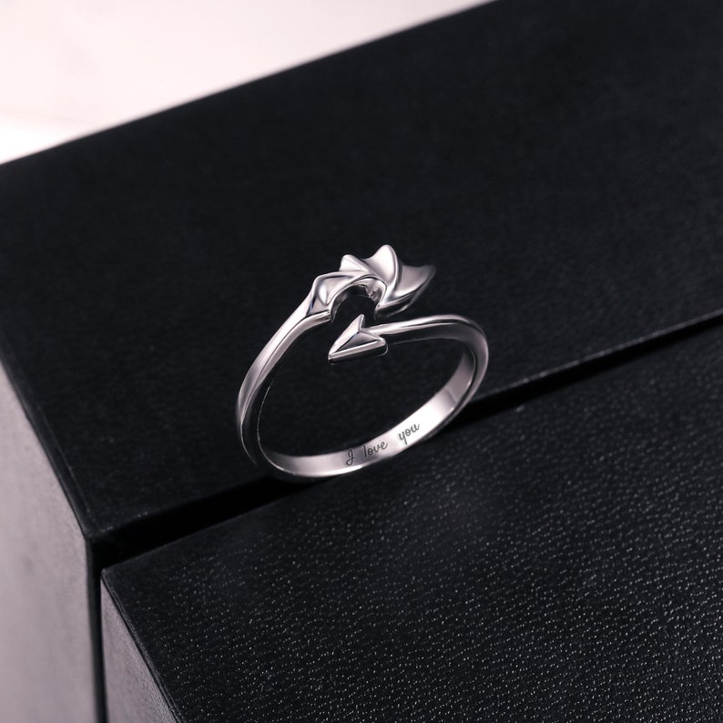 Puede incluir: Un anillo de plata con un dise&ntilde;o de flecha y la inscripci&oacute;n "Te amo".